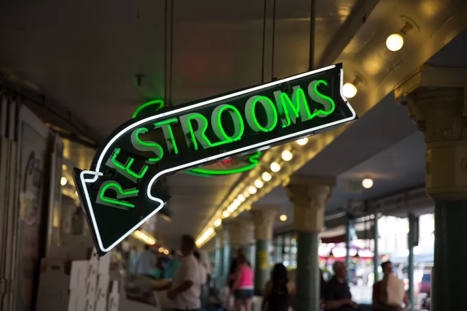Close-up of green neon Restrooms sign.